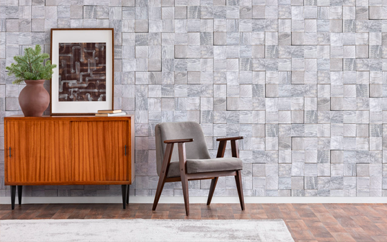 White/gray mosaic wood tiles make up decorative wall with chair, cabinet and white rug in front. 