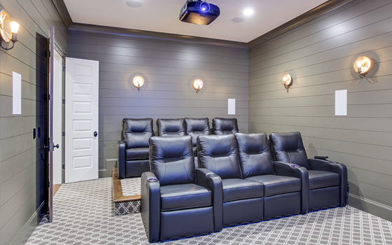 Grey, Smooth Prime MDF panels line walls of home theater room with black theater chairs. A projector hangs overhead.